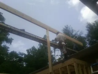 Carpenter setting a ridge beam over a new addition frame — Ice Dam Removal by Roofing Brothers in Toano