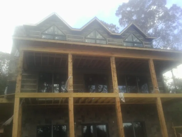 Dormers and porch framing on a large log home under construction — Roof Coating work by our crew in Toano