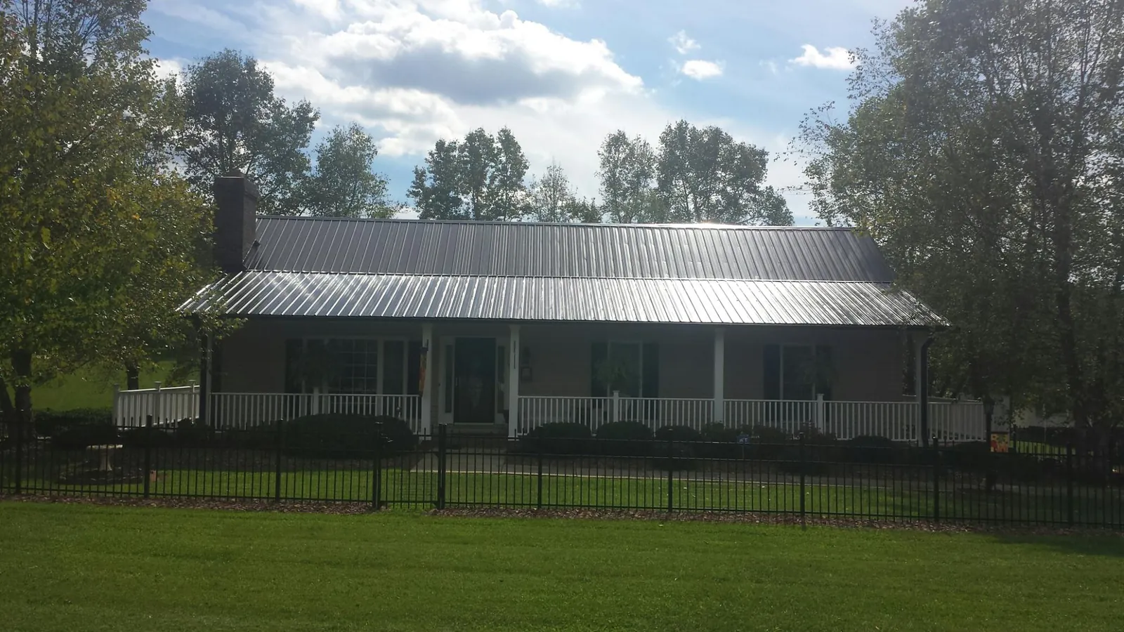 Gray metal roof on a brick ranch with a full width front porch — Gutter Guard Installation work by our crew in Toano