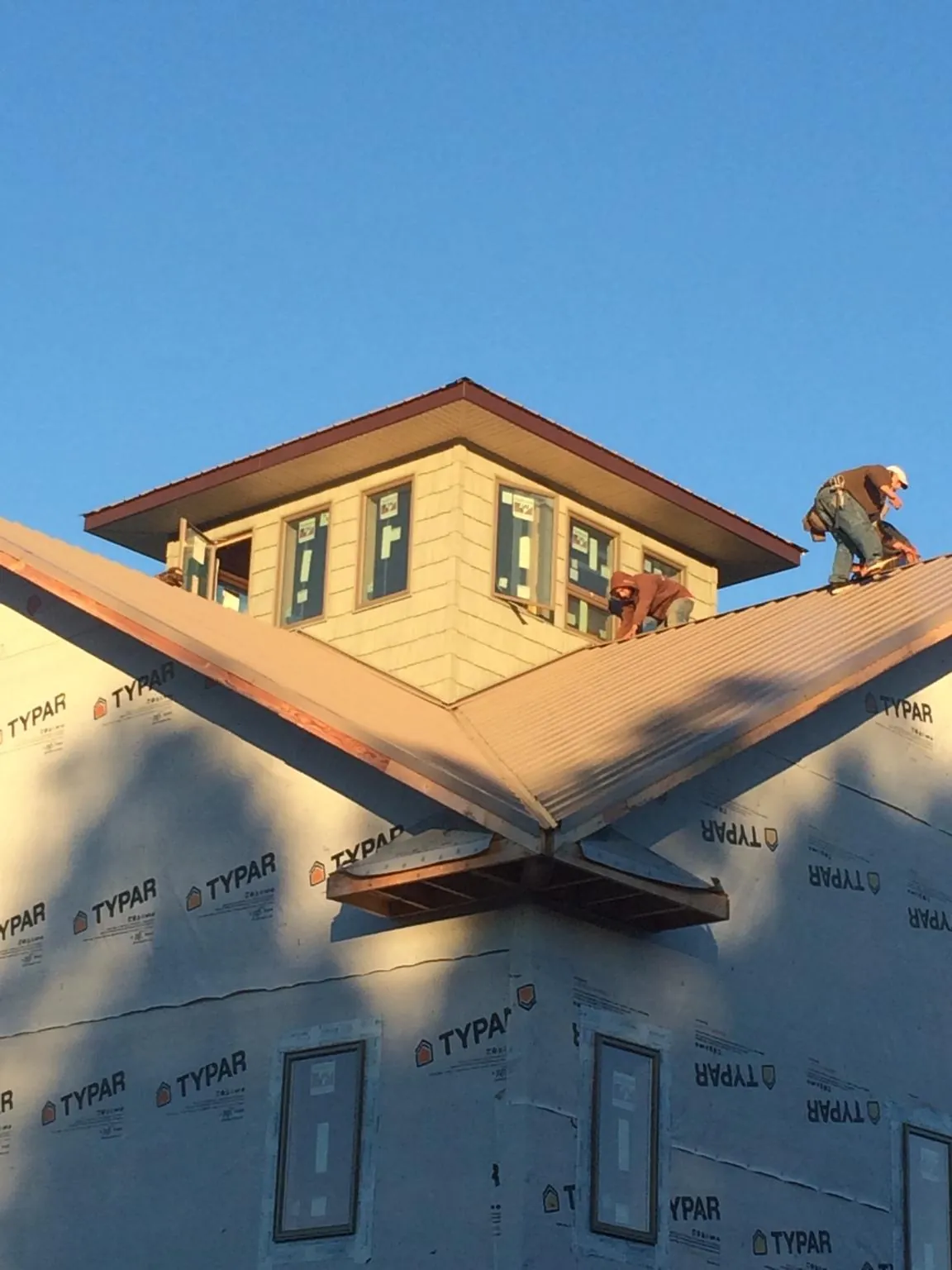 Roofers working around a rooftop cupola on a new metal roof at sunset — Roof Waterproofing in Toano by Roofing Brothers